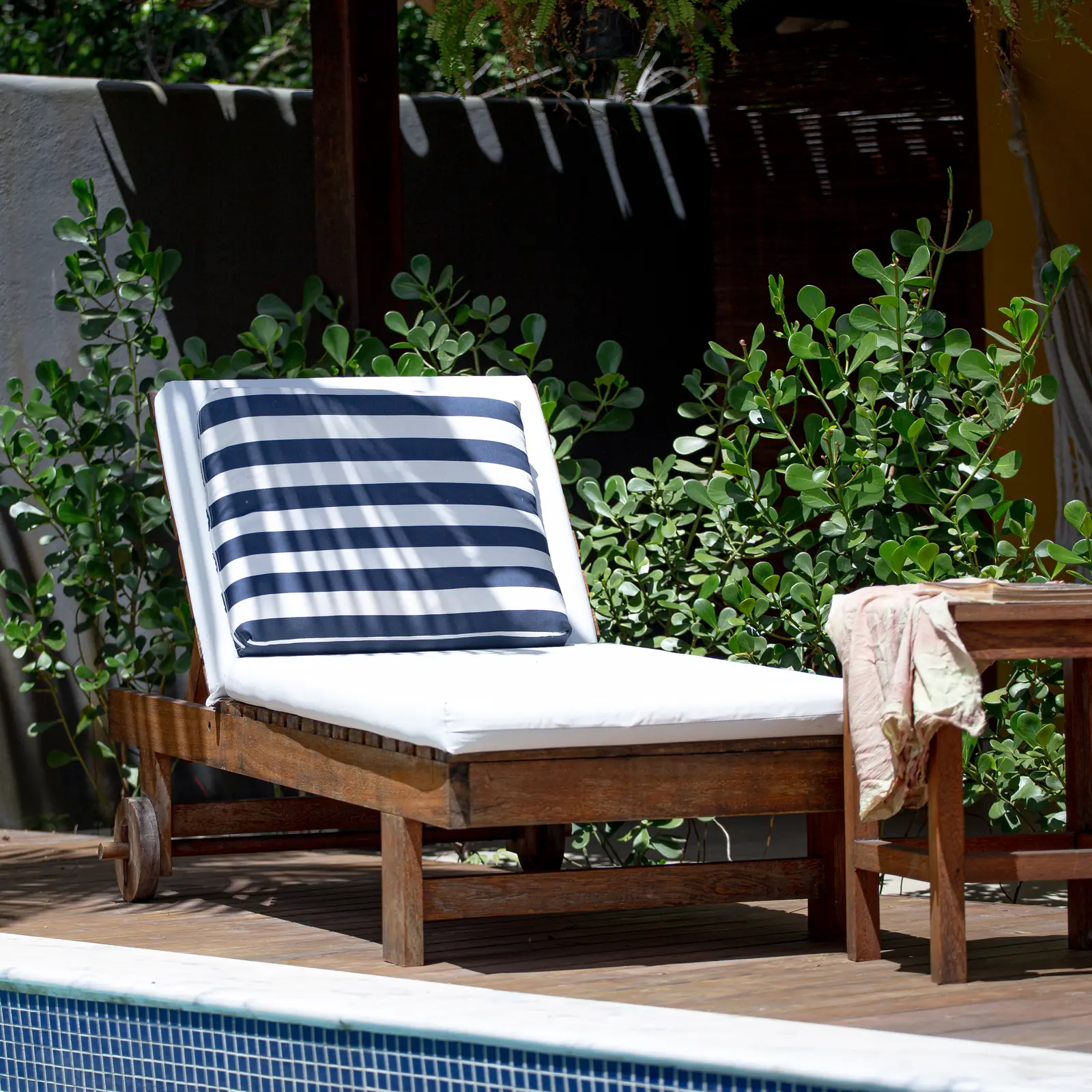 Espreguiçadeira de madeira à beira da piscina