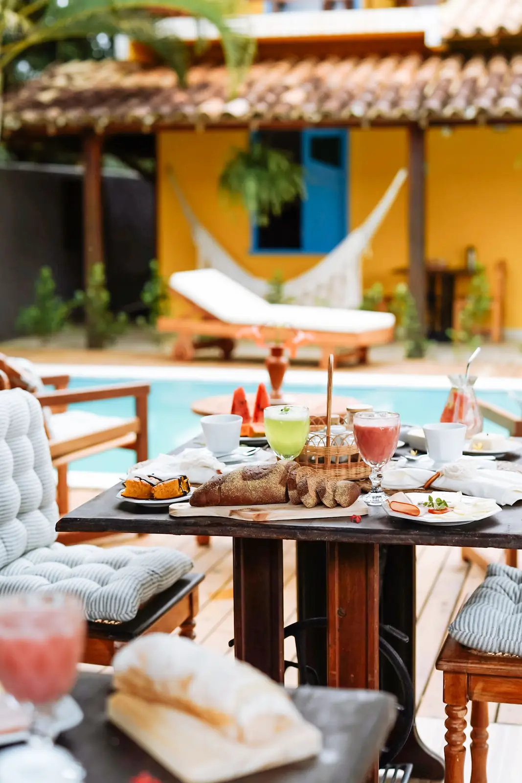 Café da manhã servido à mesa com a fachada amarela ao fundo