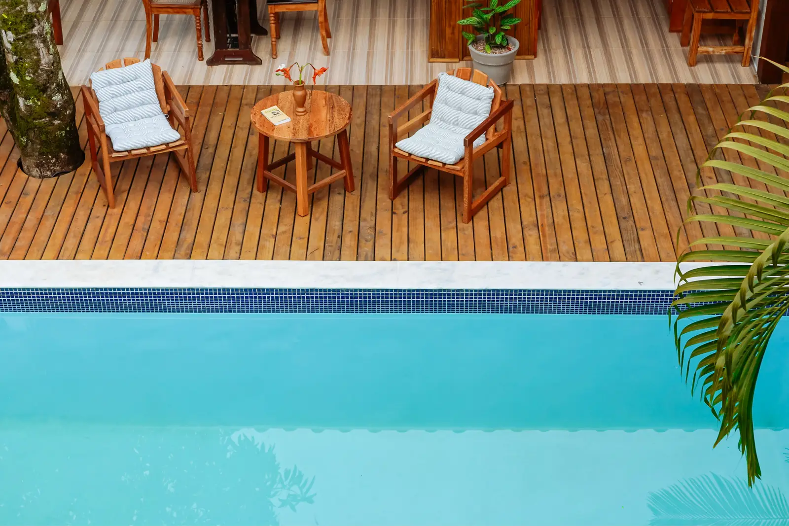 Deck de madeira com poltronas à beira da piscina