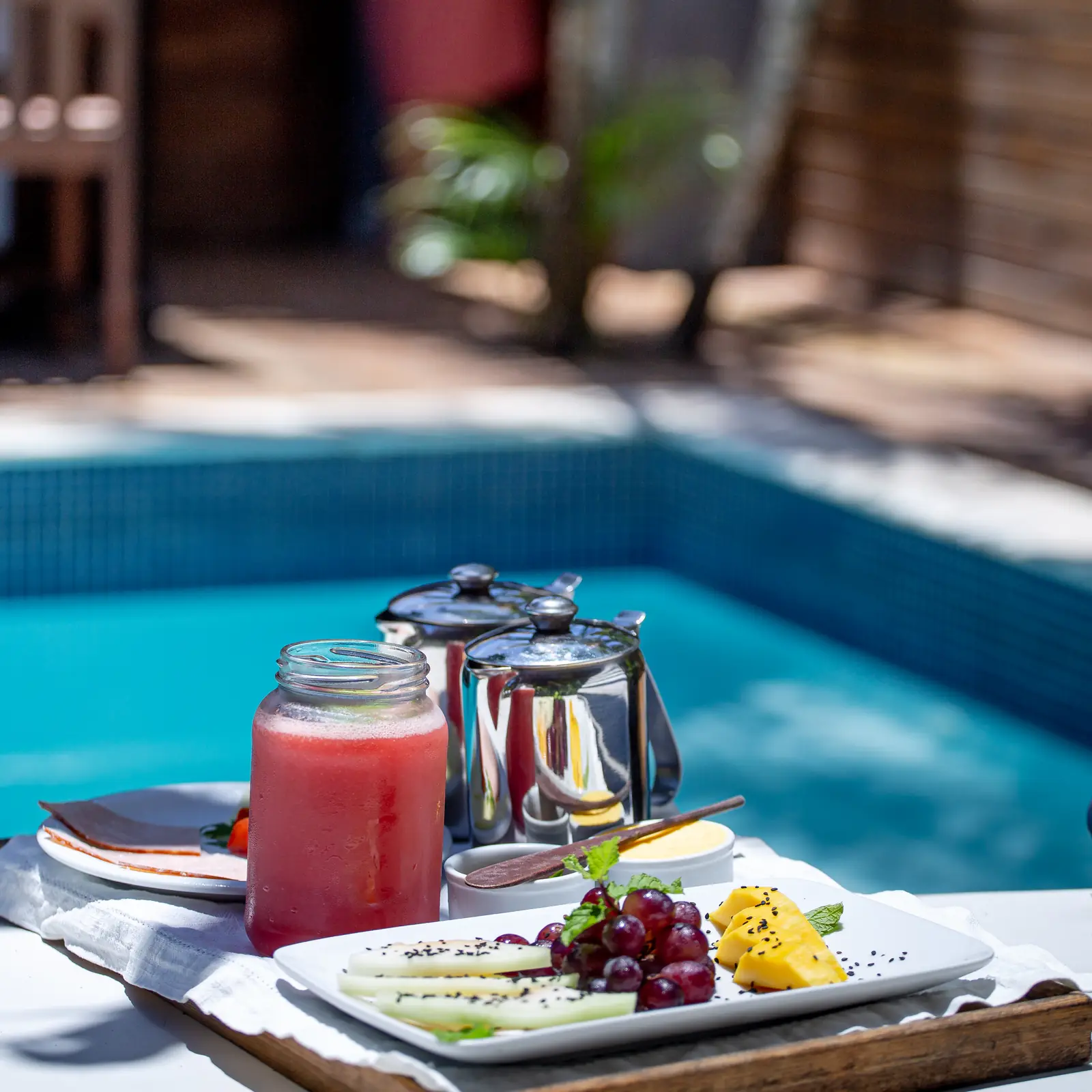 Bandeja de café da manhã com frutas e suco à beira da piscina