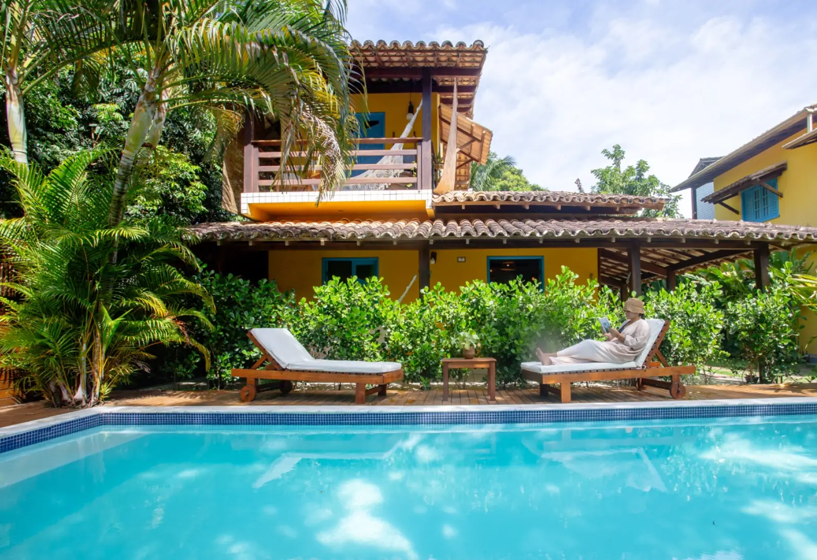 Piscina com espreguiçadeiras e o jardim tropical ao redor