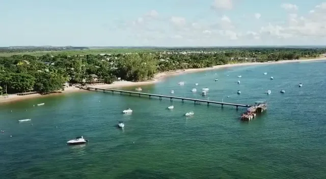 Vista aérea do píer de Barra Grande com barcos nas águas calmas da baía