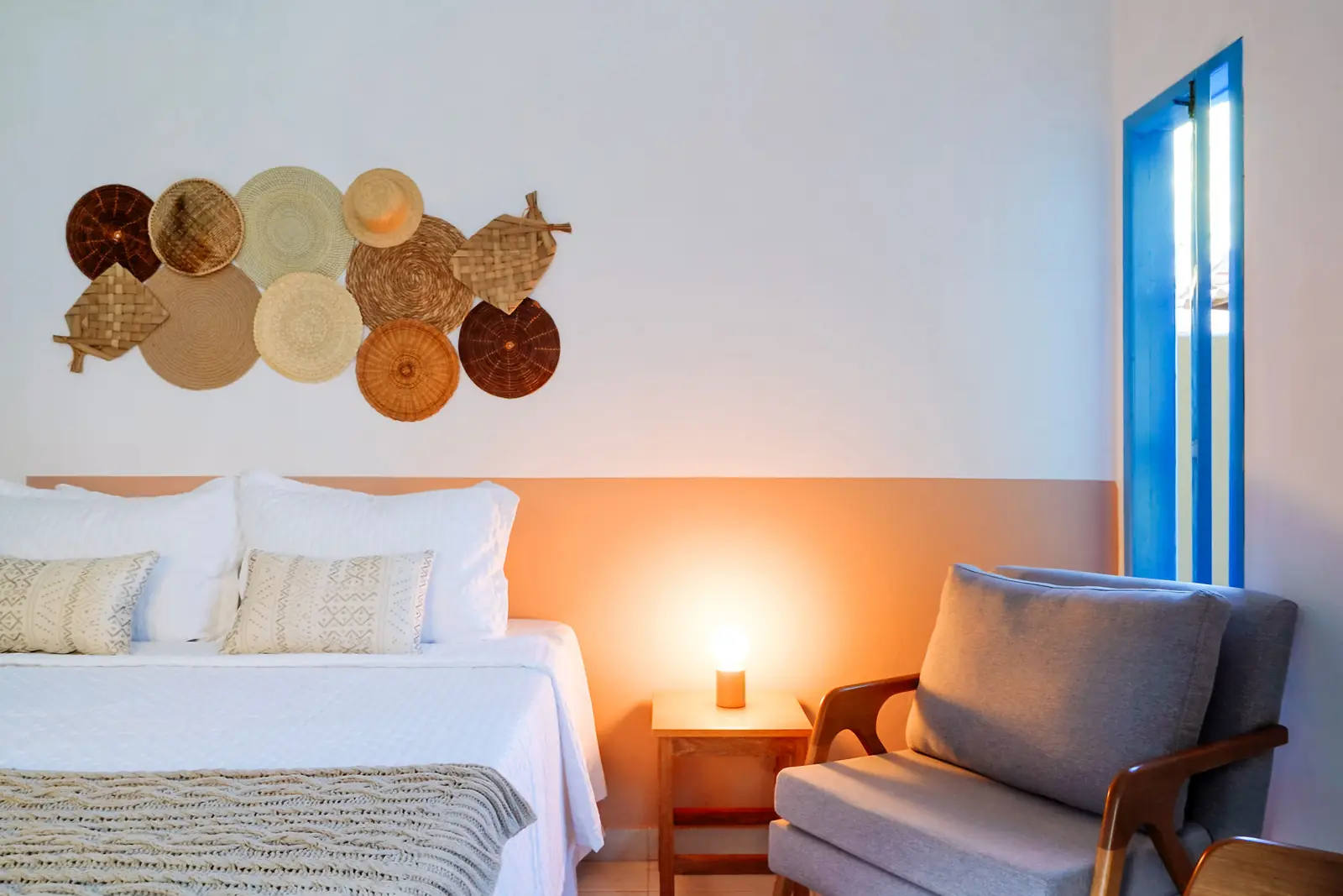 Suíte Deluxe Térreo — cama Queen com poltrona e abajur aceso