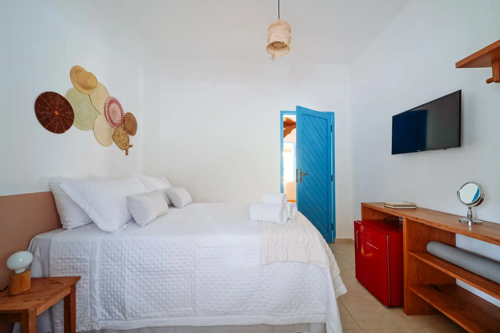 Suíte Standard — suíte térrea com cama de casal, TV e porta azul aberta