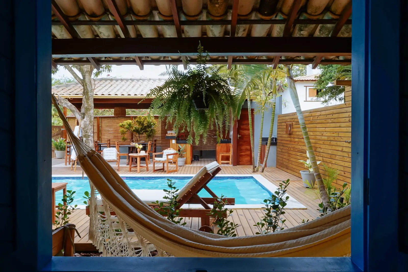 Suíte Vista Piscina Térreo — rede na varanda com a piscina e o jardim ao fundo