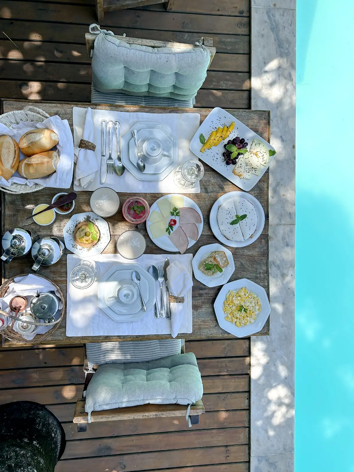 Mesa do café da manhã posta no deck junto à piscina